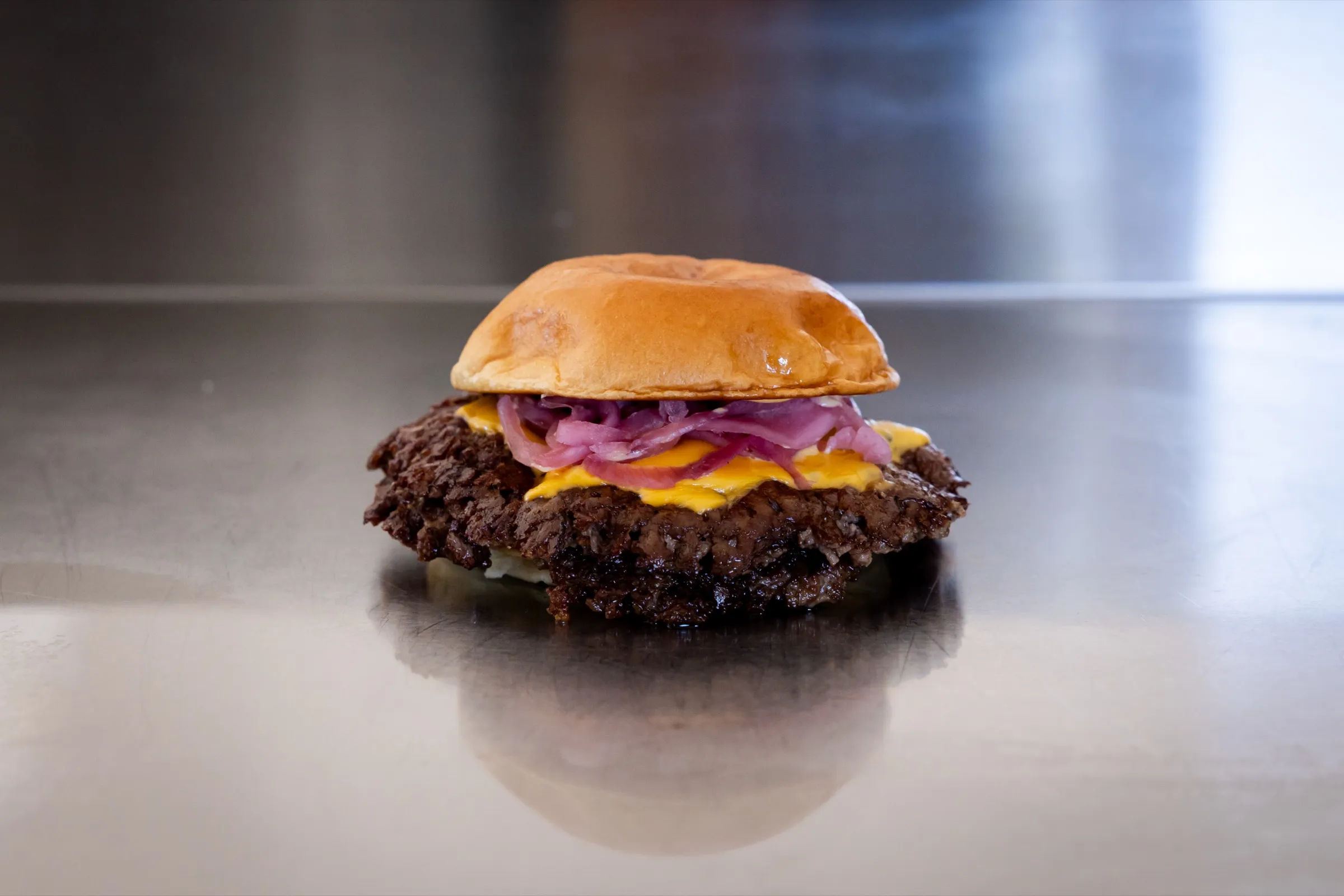 House Cheeseburger med syltede rødløg og smeltet ost på et stålbord